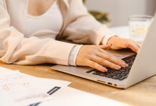 a person with manicured nails typing on laptop