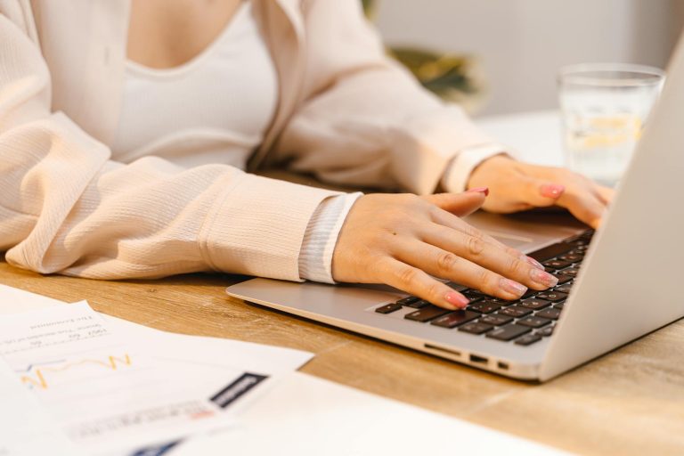 a person with manicured nails typing on laptop