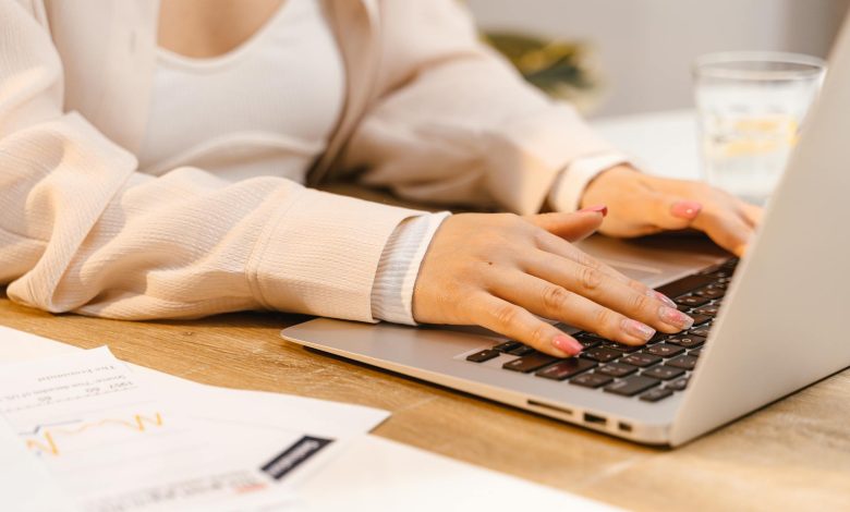 a person with manicured nails typing on laptop